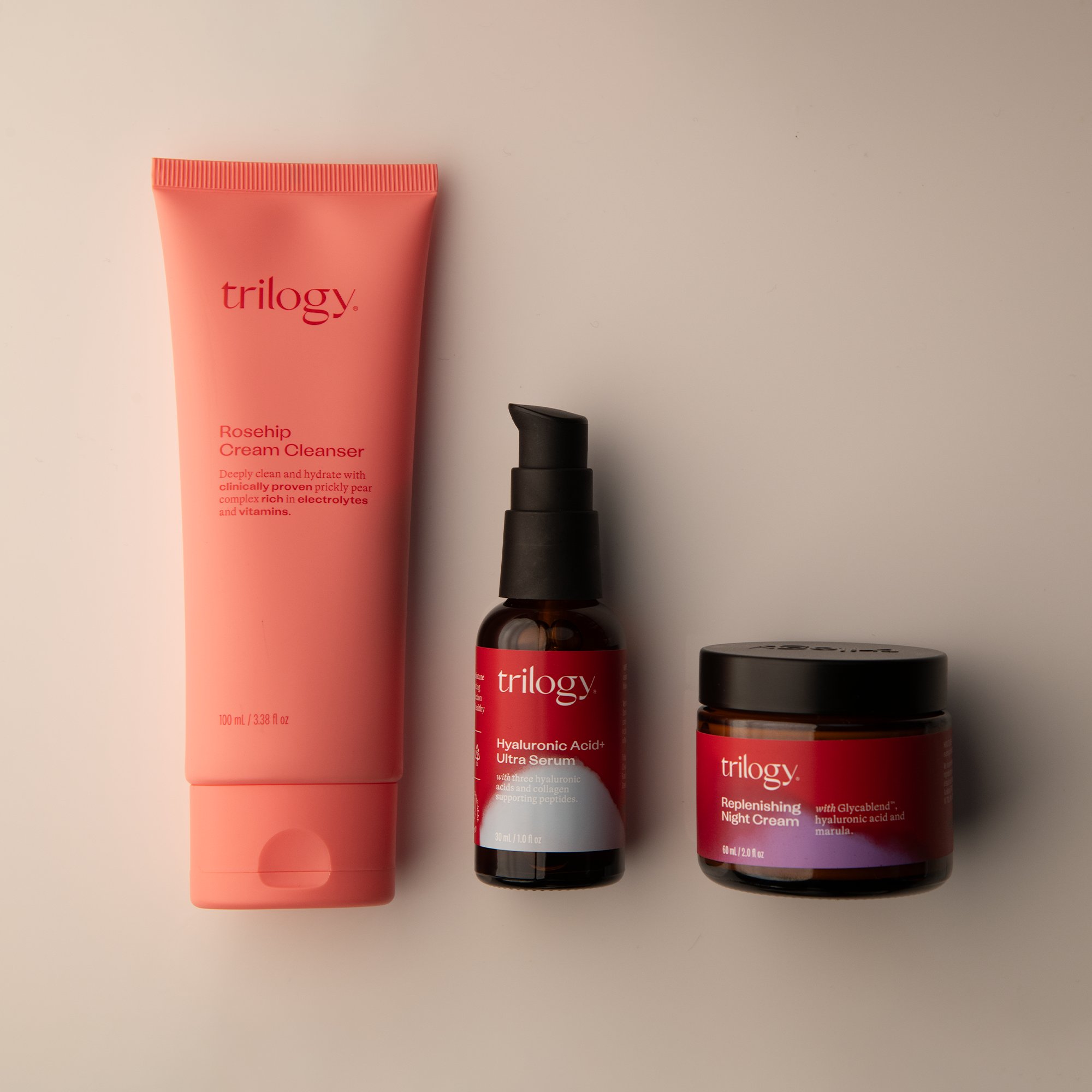 Three Trilogy skincare products on a beige background