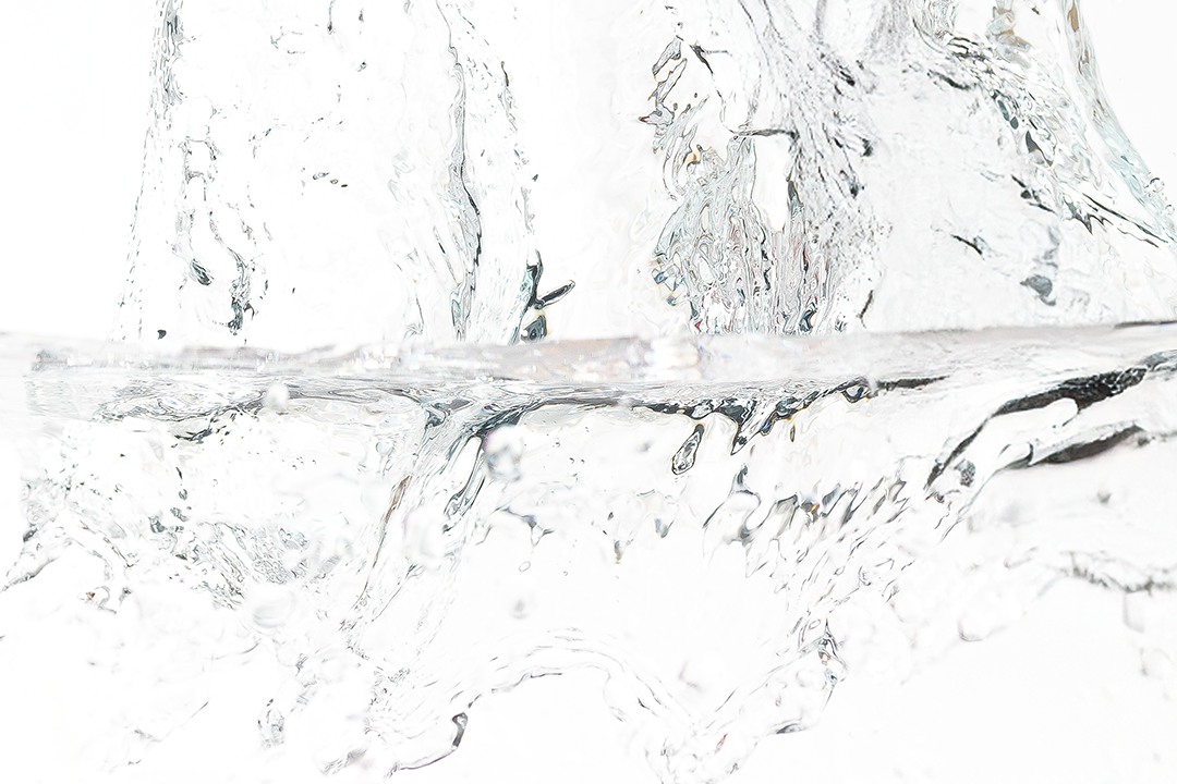 Bottle of Trilogy skincare splashing into water